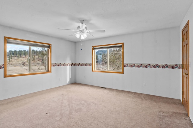 unfurnished room featuring ceiling fan, light colored carpet, and a healthy amount of sunlight