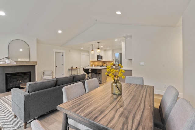 dining room with light hardwood / wood-style floors, lofted ceiling, and a tile fireplace