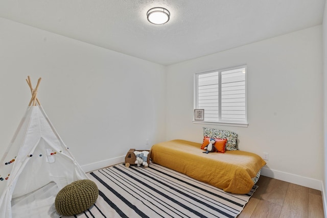 bedroom with a textured ceiling and hardwood / wood-style flooring