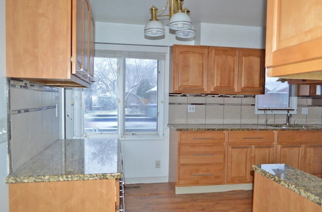 kitchen with sink, light stone countertops, light hardwood / wood-style floors, and decorative backsplash