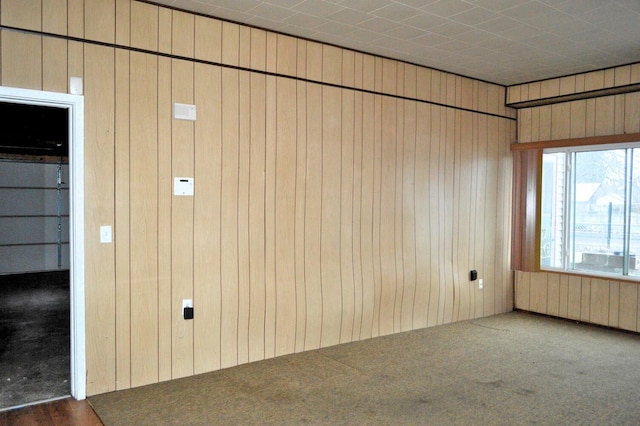 unfurnished room featuring wooden walls, radiator heating unit, and dark carpet