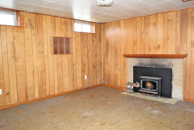 basement with wood walls, a wealth of natural light, and a wood stove