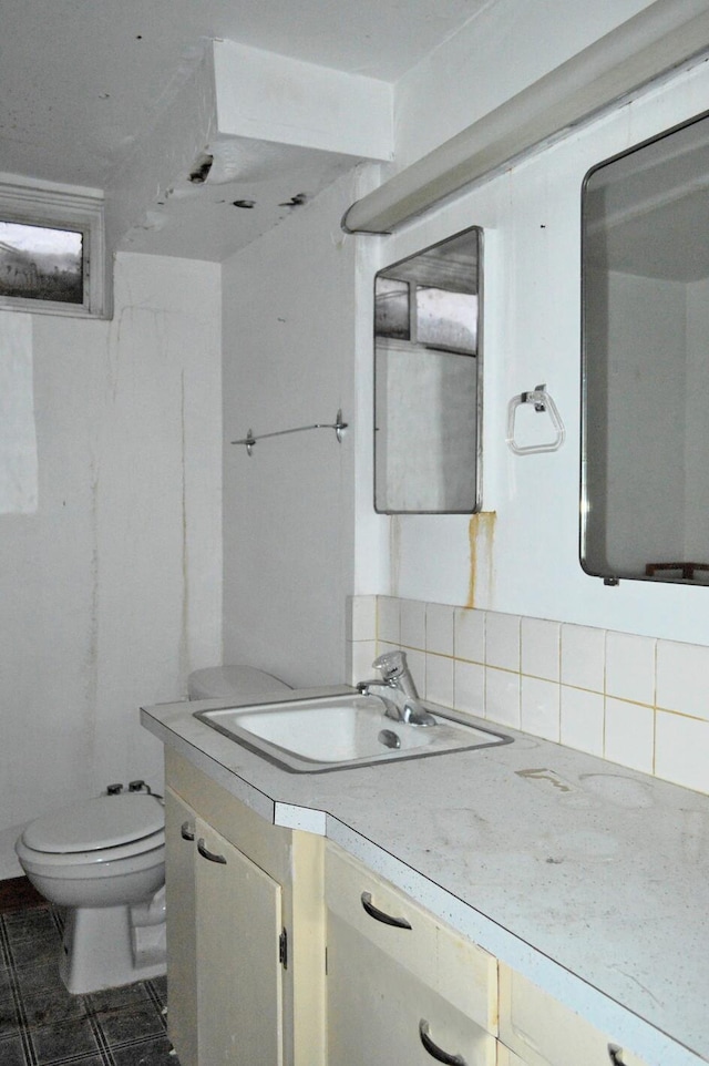 bathroom featuring toilet, vanity, and decorative backsplash