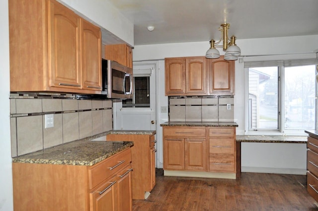 kitchen with a notable chandelier, tasteful backsplash, dark stone counters, and dark hardwood / wood-style floors