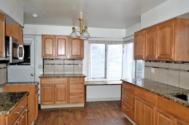 kitchen featuring decorative backsplash, dark stone countertops, a chandelier, and dark wood-type flooring