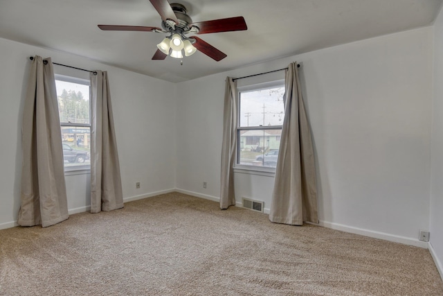 carpeted empty room with ceiling fan and plenty of natural light