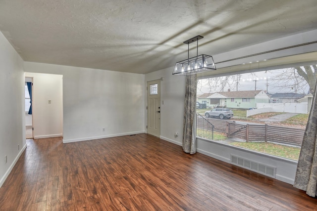 unfurnished room featuring plenty of natural light, wood-type flooring, and a textured ceiling