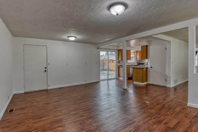 unfurnished living room featuring a textured ceiling, sink, and dark hardwood / wood-style floors