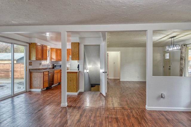 kitchen featuring a textured ceiling, stainless steel appliances, sink, dark hardwood / wood-style floors, and hanging light fixtures