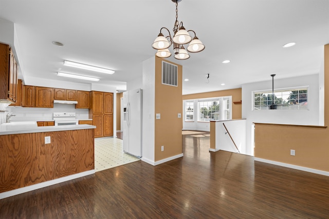 kitchen with a chandelier, pendant lighting, white appliances, and kitchen peninsula