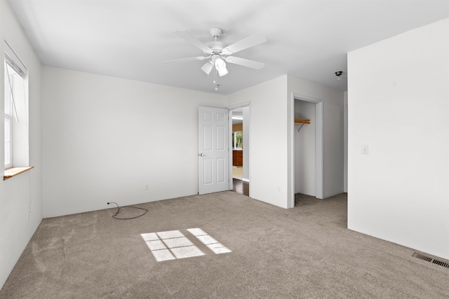 unfurnished bedroom featuring ceiling fan, light colored carpet, and a closet