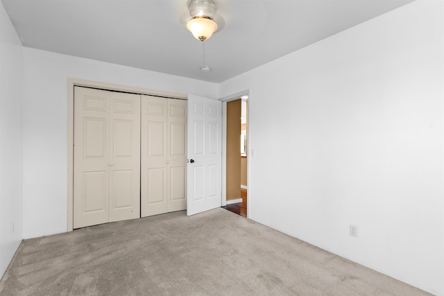 unfurnished bedroom with light colored carpet and a closet