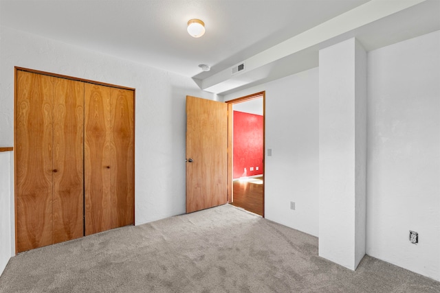 unfurnished bedroom featuring light carpet and a closet