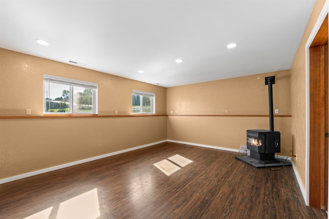 basement with dark hardwood / wood-style floors and a wood stove