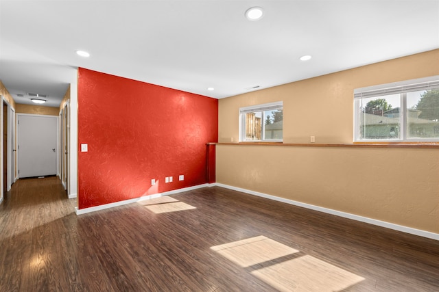 empty room featuring a healthy amount of sunlight and dark wood-type flooring