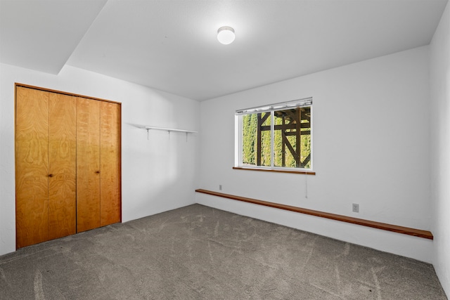 unfurnished bedroom with carpet, a closet, and baseboard heating