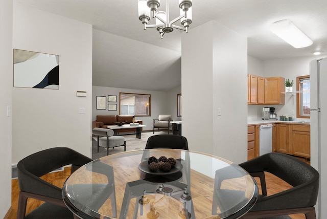 dining space featuring light hardwood / wood-style flooring, vaulted ceiling, and a notable chandelier