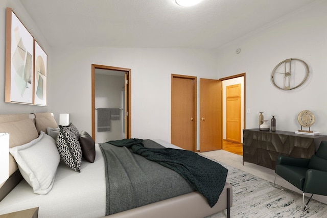 bedroom featuring ensuite bath and vaulted ceiling