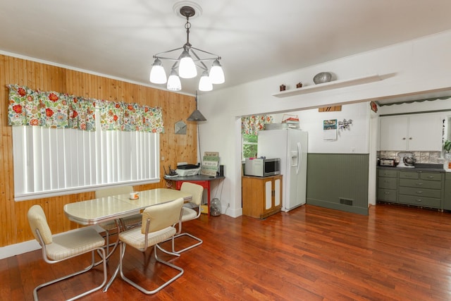 dining area featuring dark hardwood / wood-style flooring, wooden walls, plenty of natural light, and a notable chandelier