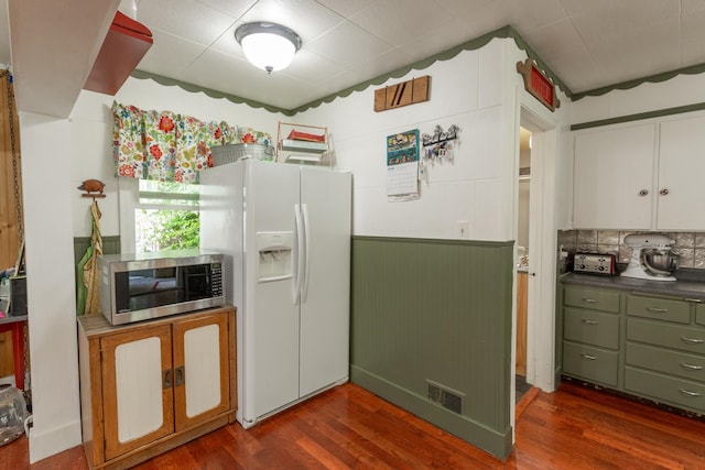 kitchen featuring white cabinetry, white fridge with ice dispenser, wooden walls, dark hardwood / wood-style floors, and decorative backsplash