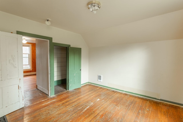 unfurnished bedroom with hardwood / wood-style floors and lofted ceiling