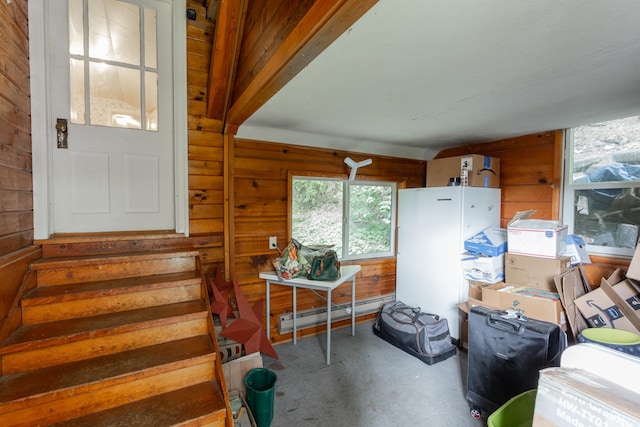 interior space with wood walls, concrete floors, and a baseboard radiator