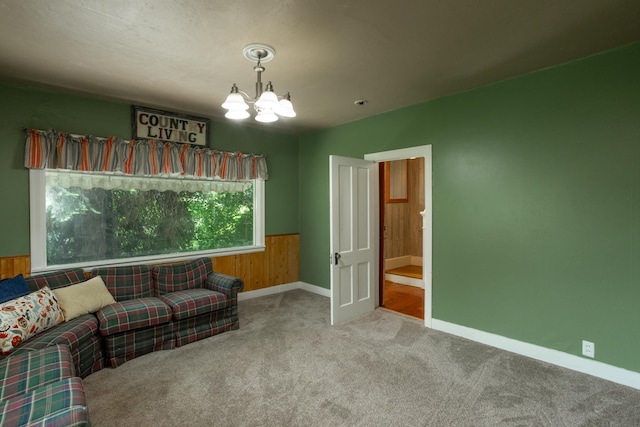 sitting room with wood walls, carpet, and a notable chandelier