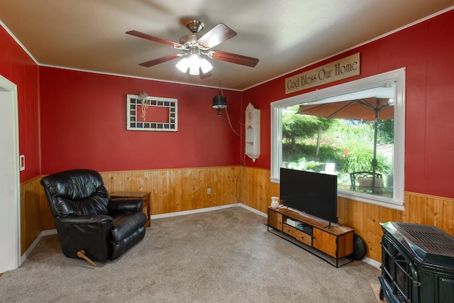 living area featuring ceiling fan, carpet floors, and wooden walls