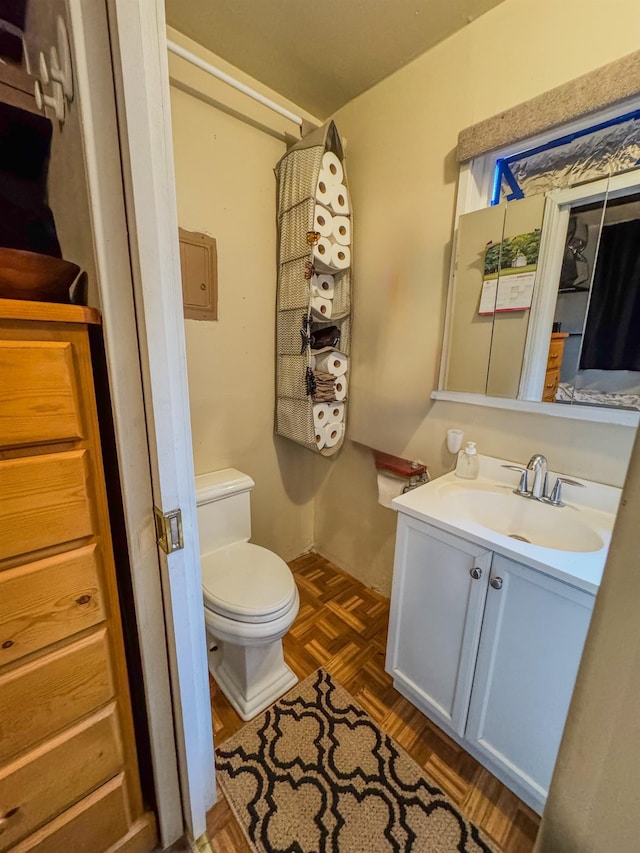 bathroom with toilet, vanity, and parquet flooring