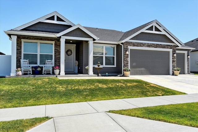 view of front of property featuring covered porch, a garage, and a front lawn