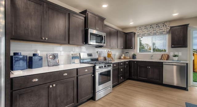 kitchen with light hardwood / wood-style flooring, stainless steel appliances, dark brown cabinets, and sink