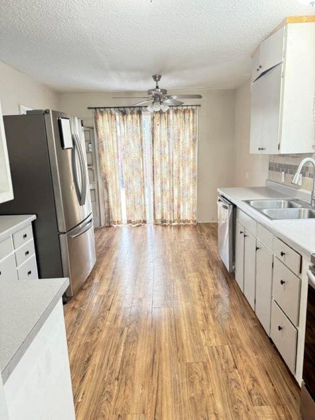 202 S Central Ave, Ione, WA 99139 - kitchen with stainless steel appliances, light wood-style flooring, light countertops, a textured ceiling, and white cabinets