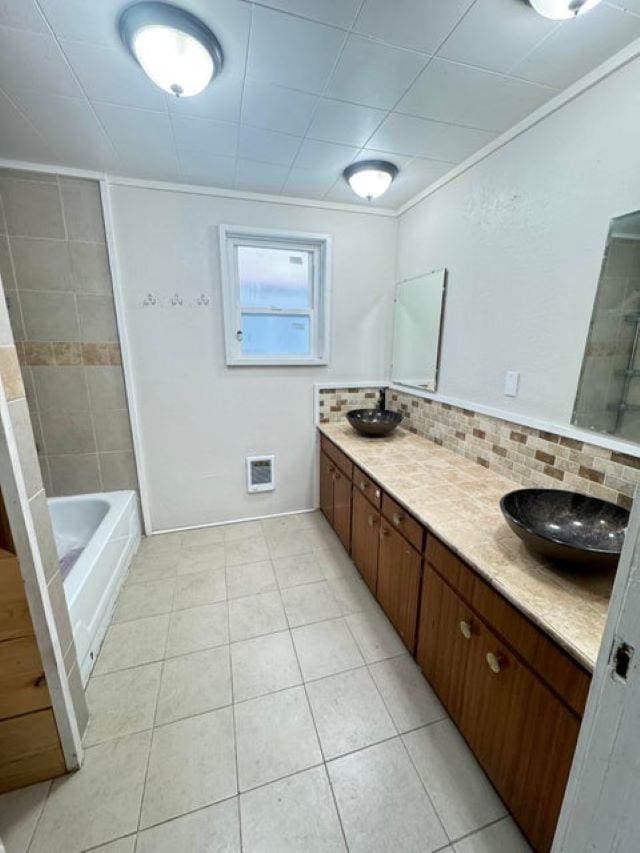 bathroom featuring vanity, tile patterned floors, ornamental molding, tasteful backsplash, and shower / bath combination