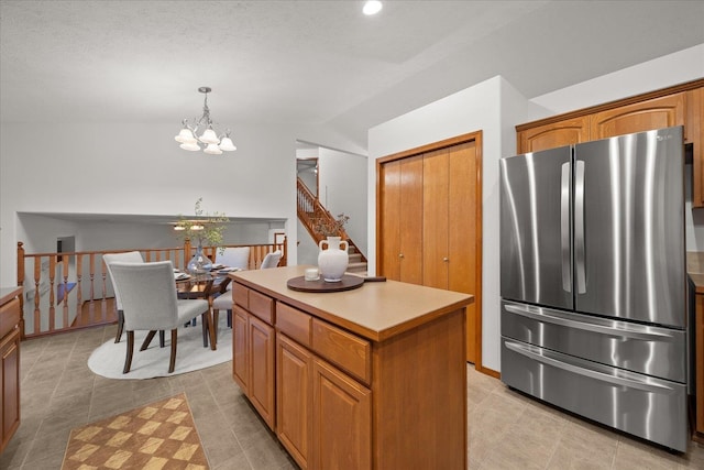 kitchen with a center island, hanging light fixtures, vaulted ceiling, stainless steel refrigerator, and a chandelier