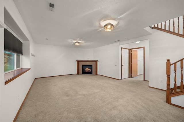 unfurnished living room featuring a fireplace, a textured ceiling, and light colored carpet