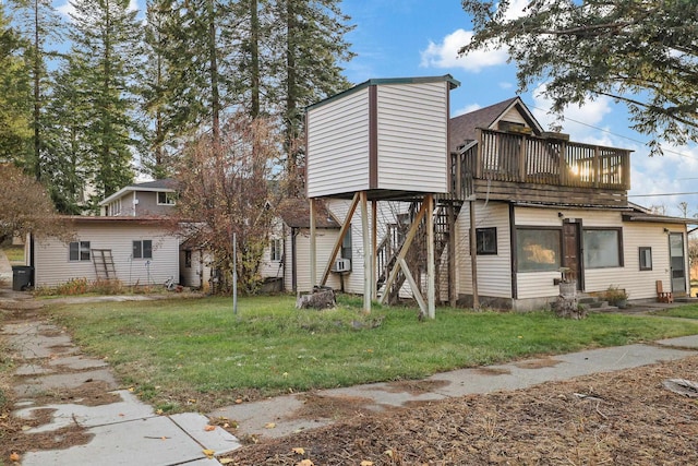 back of property with cooling unit, a balcony, and a yard