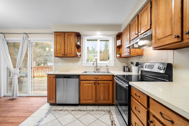 kitchen featuring decorative backsplash, light wood-type flooring, stainless steel appliances, and sink