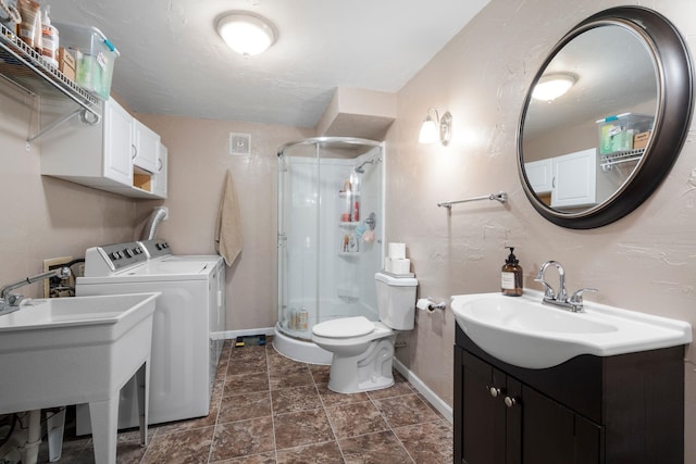 bathroom with vanity, toilet, walk in shower, and washing machine and clothes dryer