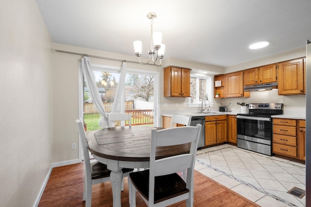 kitchen featuring sink, light wood-type flooring, a notable chandelier, and appliances with stainless steel finishes