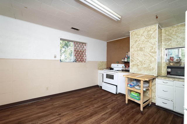 kitchen featuring dark wood-style floors, a wainscoted wall, white electric range oven, light countertops, and visible vents