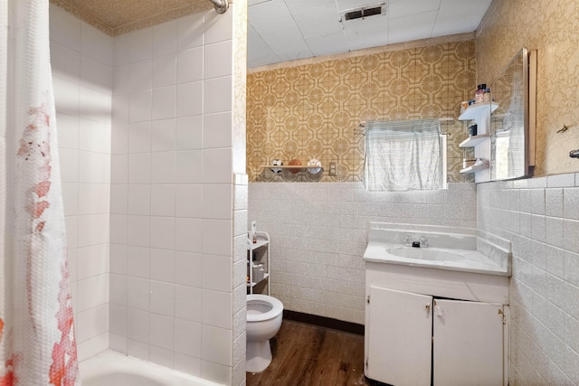 bathroom featuring toilet, wood finished floors, vanity, visible vents, and shower / bath combo