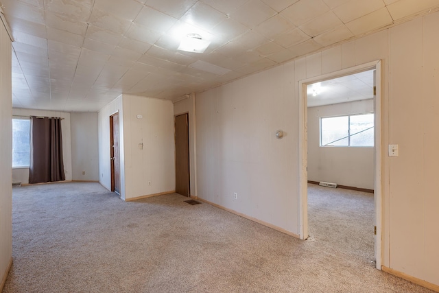 unfurnished room featuring light colored carpet, visible vents, and baseboards