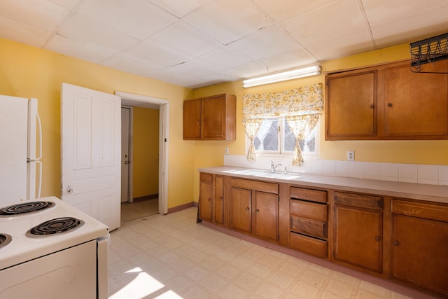 kitchen featuring white appliances, brown cabinets, light countertops, light floors, and a sink