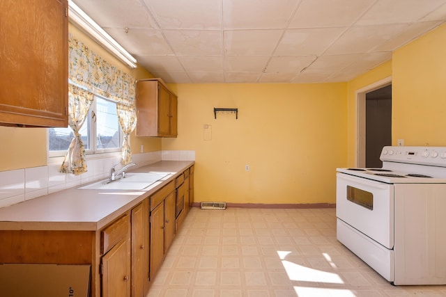 kitchen with a sink, baseboards, light countertops, light floors, and white electric range oven