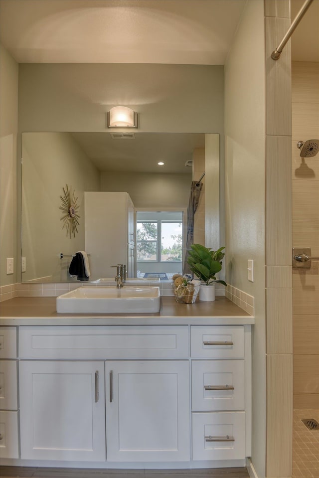 bathroom with a tile shower and vanity