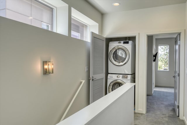 clothes washing area featuring stacked washer / drying machine and light colored carpet