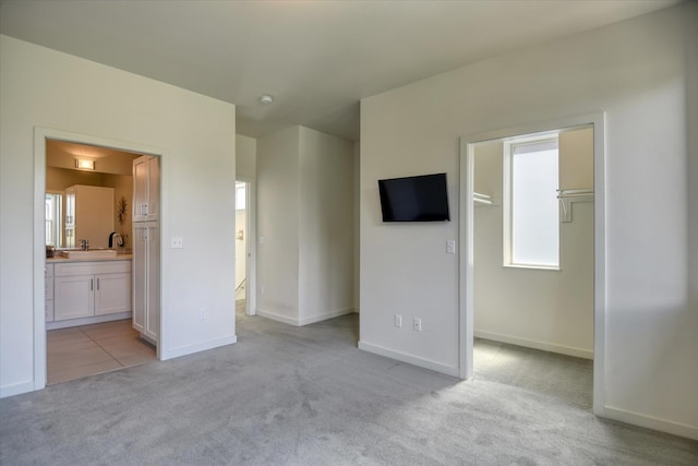 unfurnished bedroom featuring multiple windows, ensuite bathroom, and light colored carpet