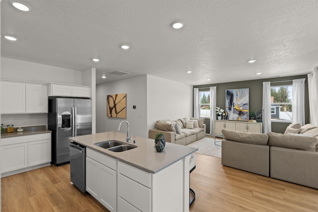 kitchen with open floor plan, stainless steel appliances, a sink, and light wood-style floors