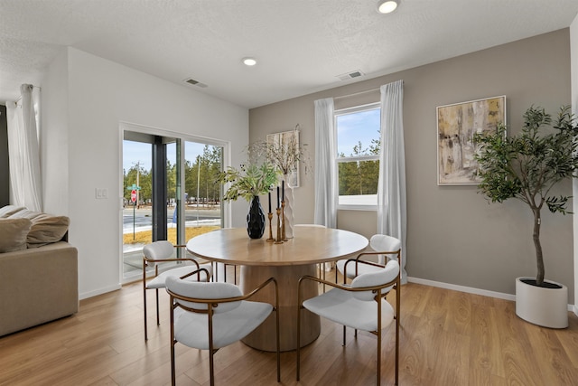 dining space with visible vents, light wood-style flooring, and baseboards