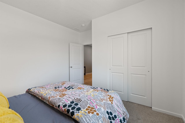 bedroom with a closet, light colored carpet, and baseboards